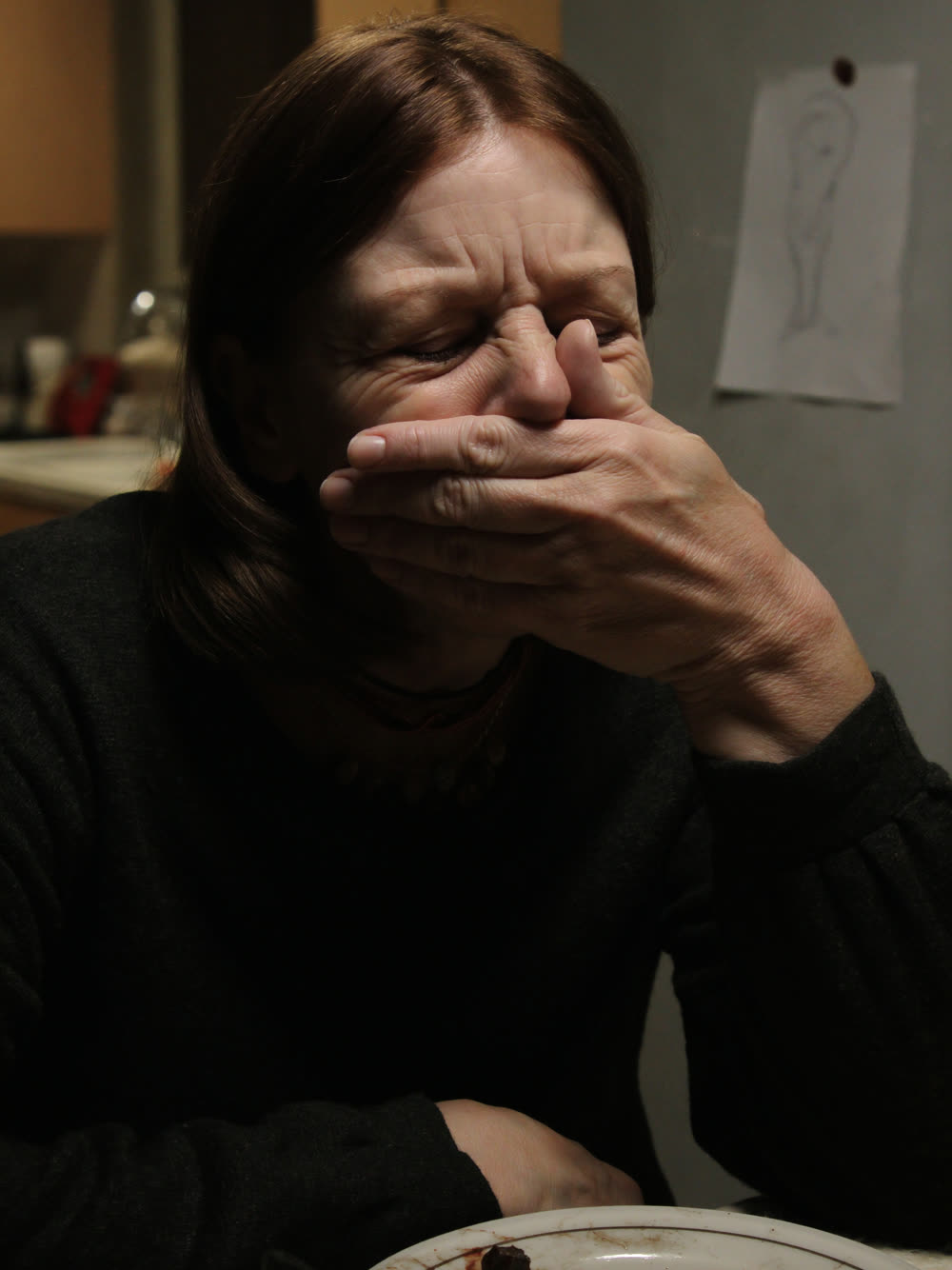 Une femme assise à sa table, le visage dans la main